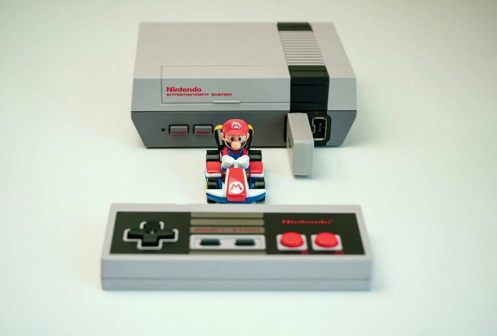 Recuerdo Paraíso Gaming: Nintendo NES con mando clásico y figura de Mario Kart